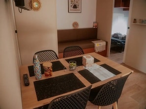 A dining area with a wooden table, black mesh chairs, a remote control, a decorative vase, and a framed picture on the wall. - ZEcamping 3 étoiles piscine chauffée club enfant hammam locatif clim (Florac)