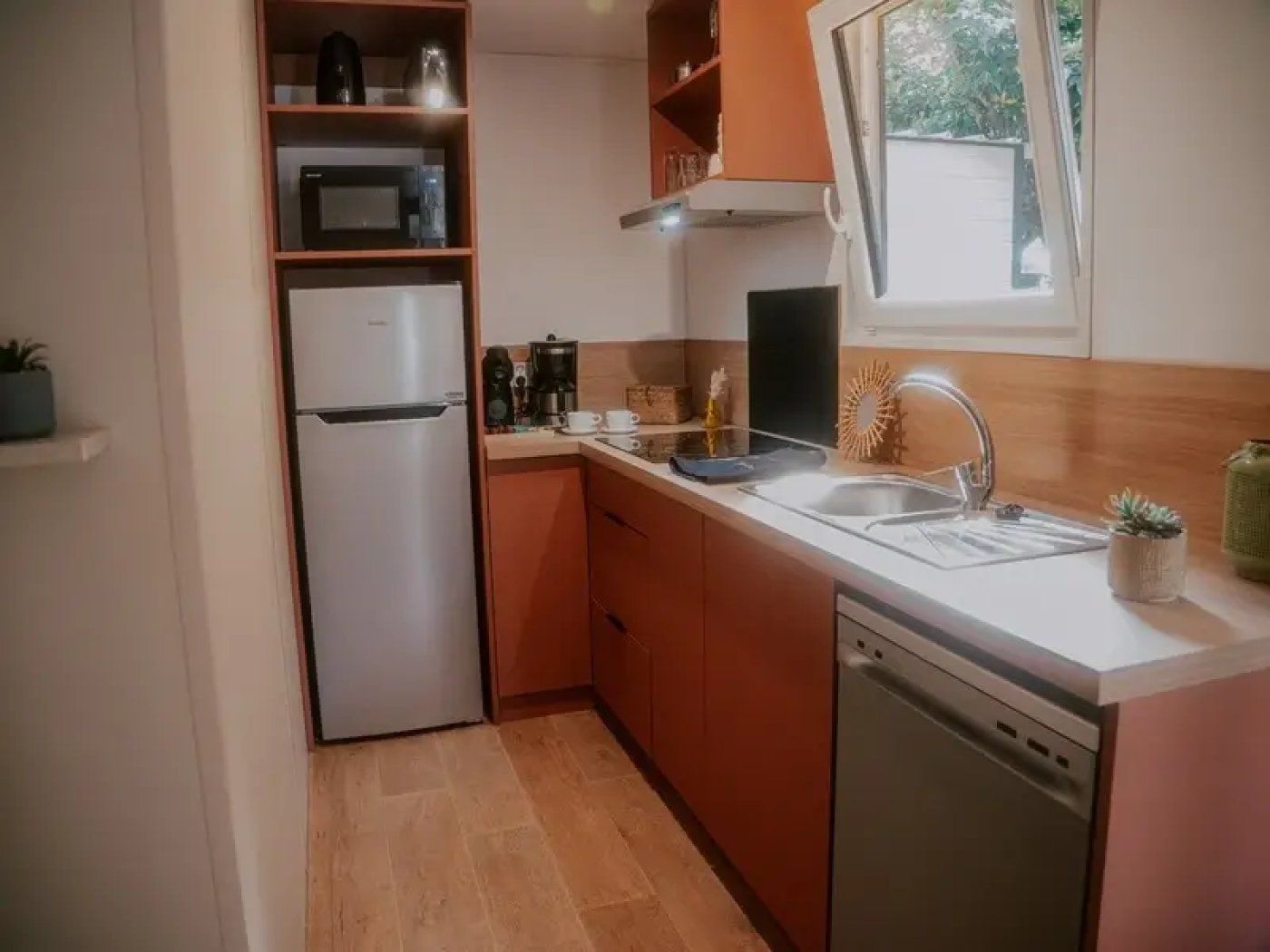 A compact kitchen with a built-in microwave, a refrigerator, a sink, and a dishwasher.
