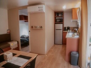 Ett kompakt bostadsutrymme med ett litet kök, en matplats och en liten sittgrupp.
