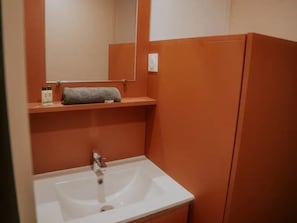 Une salle de bain avec un lavabo blanc, un miroir et une serviette posée sur une étagère.