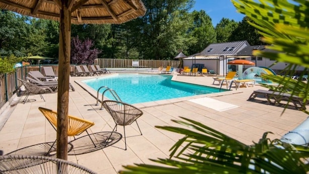 A swimming pool with lounge chairs and a shaded area. - ZEcamping 3* piscine chauffée dog friendly animations locatif clim (Florac)
