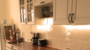 Cucina con mobili bianchi, un piano di lavoro in legno, un lavello in acciaio inossidabile e una macchina da caffè.