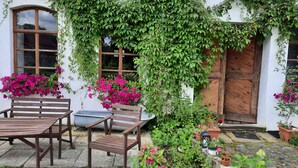 Un rustico cottage con una porta in legno, una finestra con cornice di legno e una panchina.