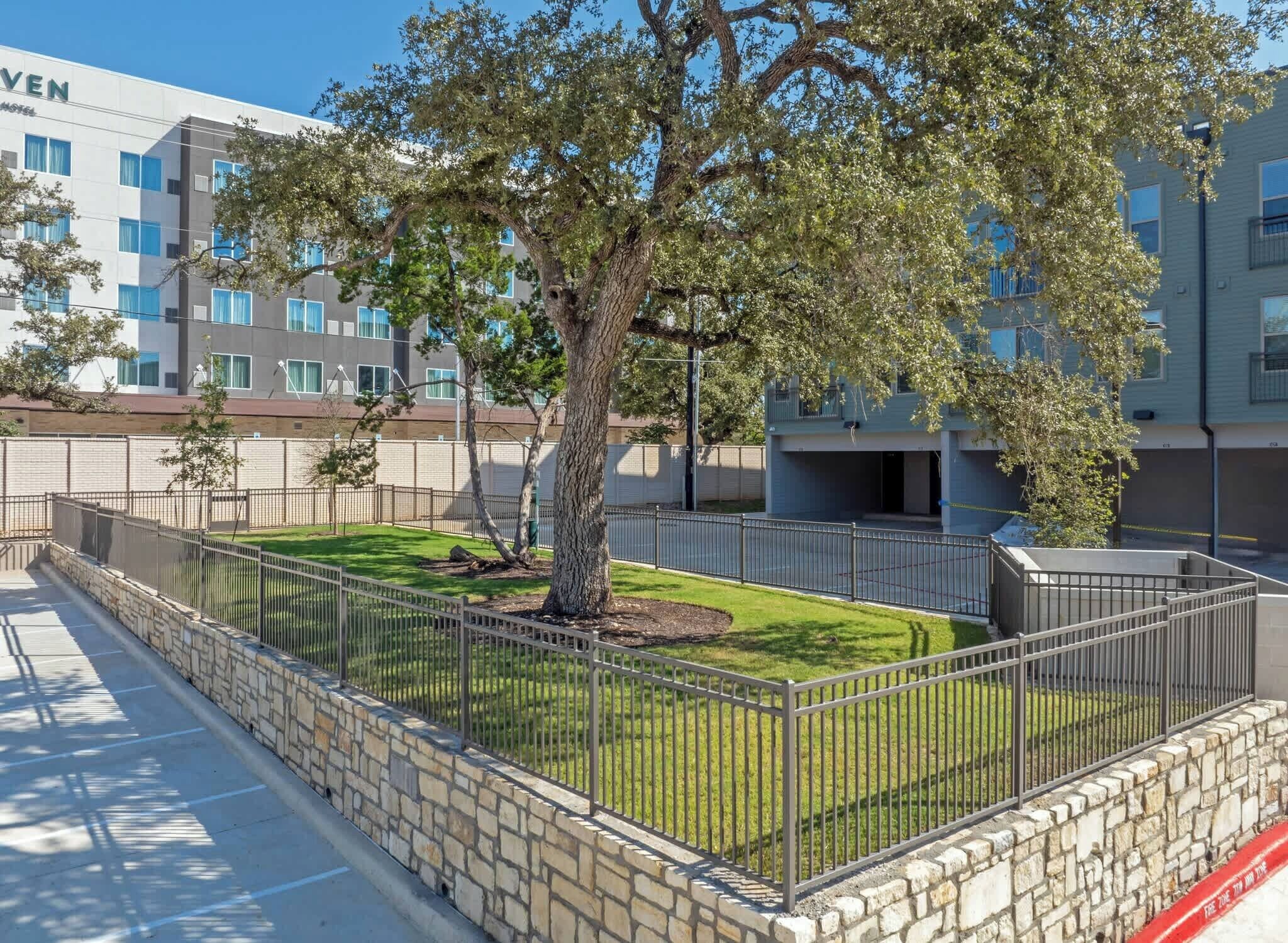A modern hotel with a large tree in the courtyard, stone walls, and a clear view of the building's exterior.