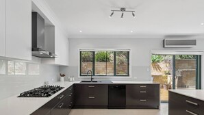Een moderne keuken met een centraal kookeiland, geïntegreerde apparatuur en een groot raam met uitzicht op de omgeving.