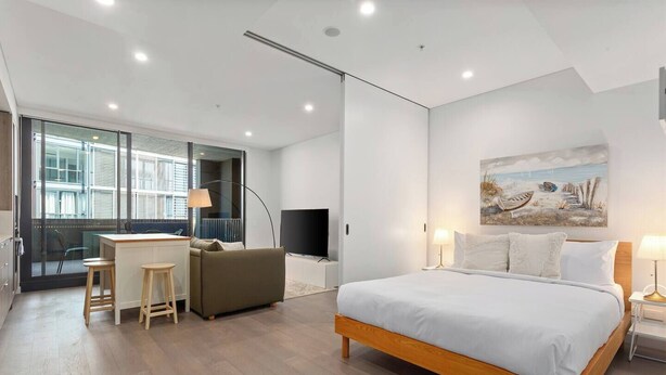 Ein modernes Hotelzimmer mit einem großen Bett, einem Schreibtisch mit zwei Stühlen, einem Fernseher und einem Bild an der Wand.