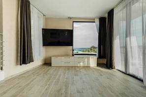 A modern living room with a flat-screen TV mounted on the wall, a large window with a view of the outdoors, and a wooden floor. - Villa Morska vila with pool and spectacular views in a small fishing village. (Vinišće)