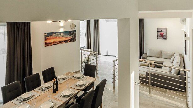 A modern dining area with a high ceiling and a staircase leading to an upper level. - Villa Morska vila with pool and spectacular views in a small fishing village. (Vinišće)