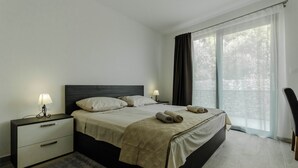 A modern bedroom with a large bed, bedside tables with lamps, a rug, and a view of trees through the window. - Villa Morska vila with pool and spectacular views in a small fishing village. (Vinišće)