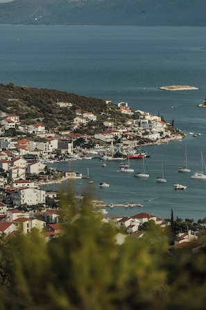 A coastal town with buildings along the waterfront, boats docked at the marina, and a small island in the distance. - Villa Morska vila with pool and spectacular views in a small fishing village. (Vinišće)