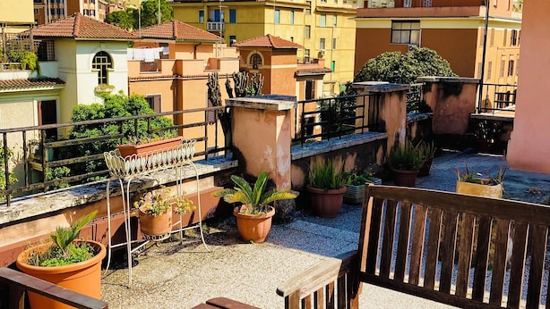 Une terrasse sur le toit, aménagée avec des meubles en bois, des plantes en pot et offrant une vue sur les bâtiments environnants.
