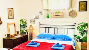 Une chambre à coucher avec un lit, une table de chevet, une lampe, une chaise, une fenêtre avec des rideaux et une horloge au mur.