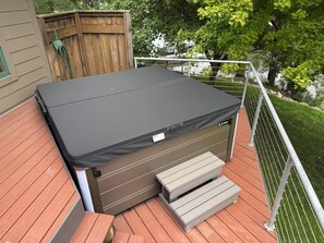 Un bain à remous doté d’un couvercle, d’un escalier et d’une terrasse en bois.