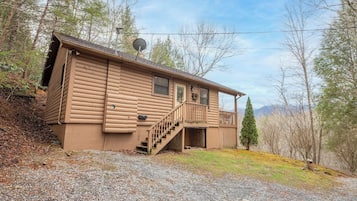 A log cabin with a balcony, a staircase, and a satellite dish.