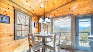 A wooden interior with a round dining table, four chairs, and a chandelier. - Cozy Mountain Cabin w/ VIEWS | Hot Tub + Fireplace (Cosby)