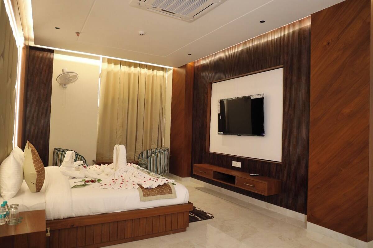 Ein modernes Schlafzimmer mit einem großen Bett, einem flachbildfernseher an der Wand und einer Wandverkleidung aus Holz.