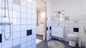 Een moderne badkamer met douche, toilet en wastafel.