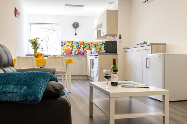A modern living room with a sofa, a coffee table, and a view of the kitchen.