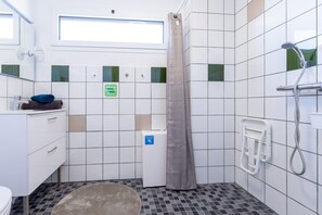 Une salle de bain équipée d’une douche, de toilettes, d’un lavabo, d’une serviette et d’un panneau indiquant la présence de toilettes accessibles aux personnes handicapées.