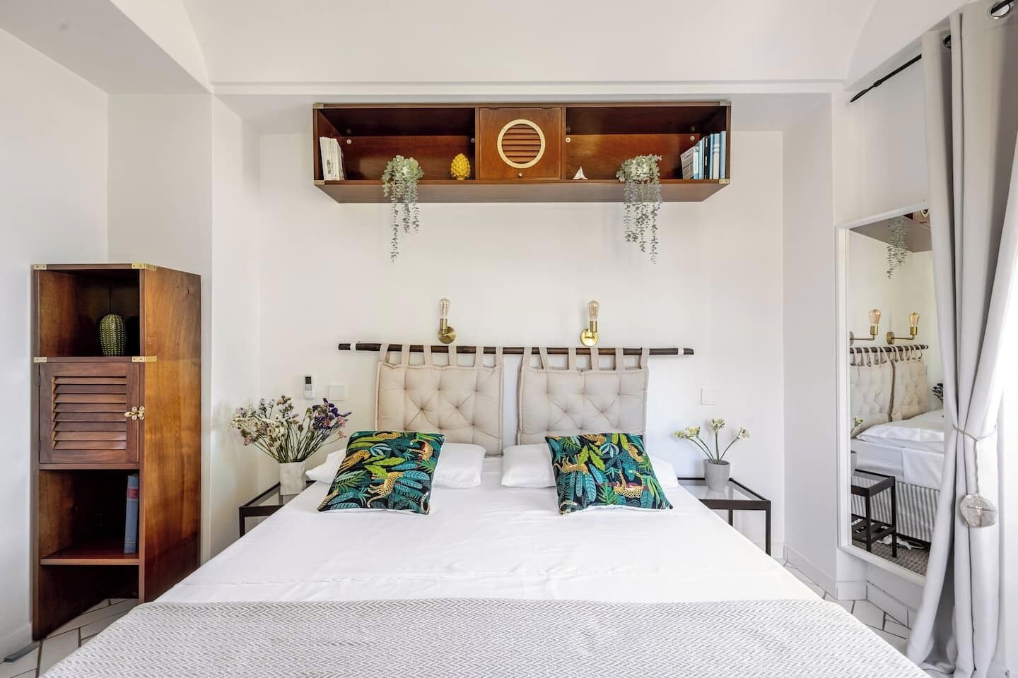 A bedroom with a large bed, a wooden cabinet, and a mirror.