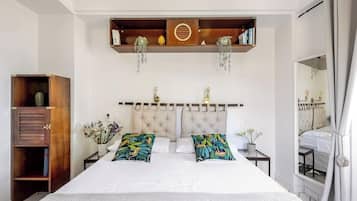 A bedroom with a large bed, a wooden cabinet, and a mirror.
