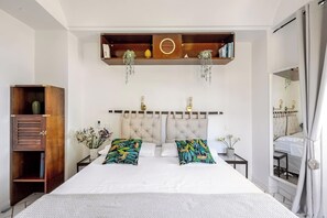 A bedroom with a large bed, a wooden cabinet, and a mirror.