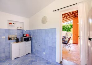 A kitchen with blue tiles, a white cabinet, a microwave, and a red kettle. - Villa Coralia - Private Garden&Sea View in Capri (Capri)