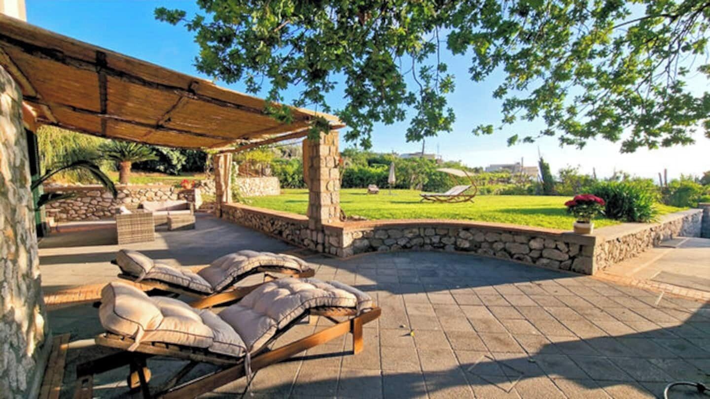 An outdoor patio with lounge chairs and a pergola structure.
