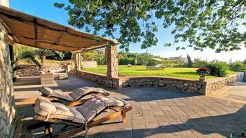 An outdoor patio with lounge chairs and a pergola structure.