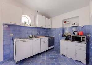 Une cuisine de taille réduite avec des meubles blancs, un évier, une cuisinière et un four à micro-ondes.