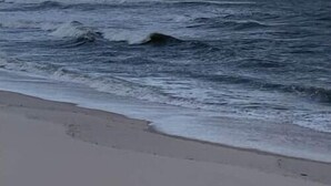 Een strand met golven en een bewolkte lucht.