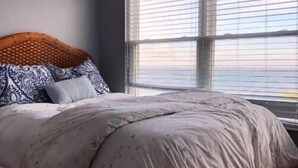 Een slaapkamer met een groot bed, een houten hoofdeinde en een raam met zonwering.