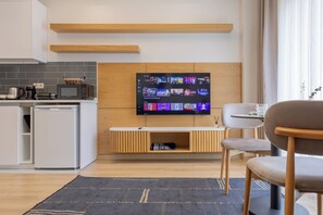 A modern kitchen with a flat-screen TV mounted on the wall, a coffee maker, and a microwave. - New Flat near Cevahir Mall, Şişli (İstanbul)