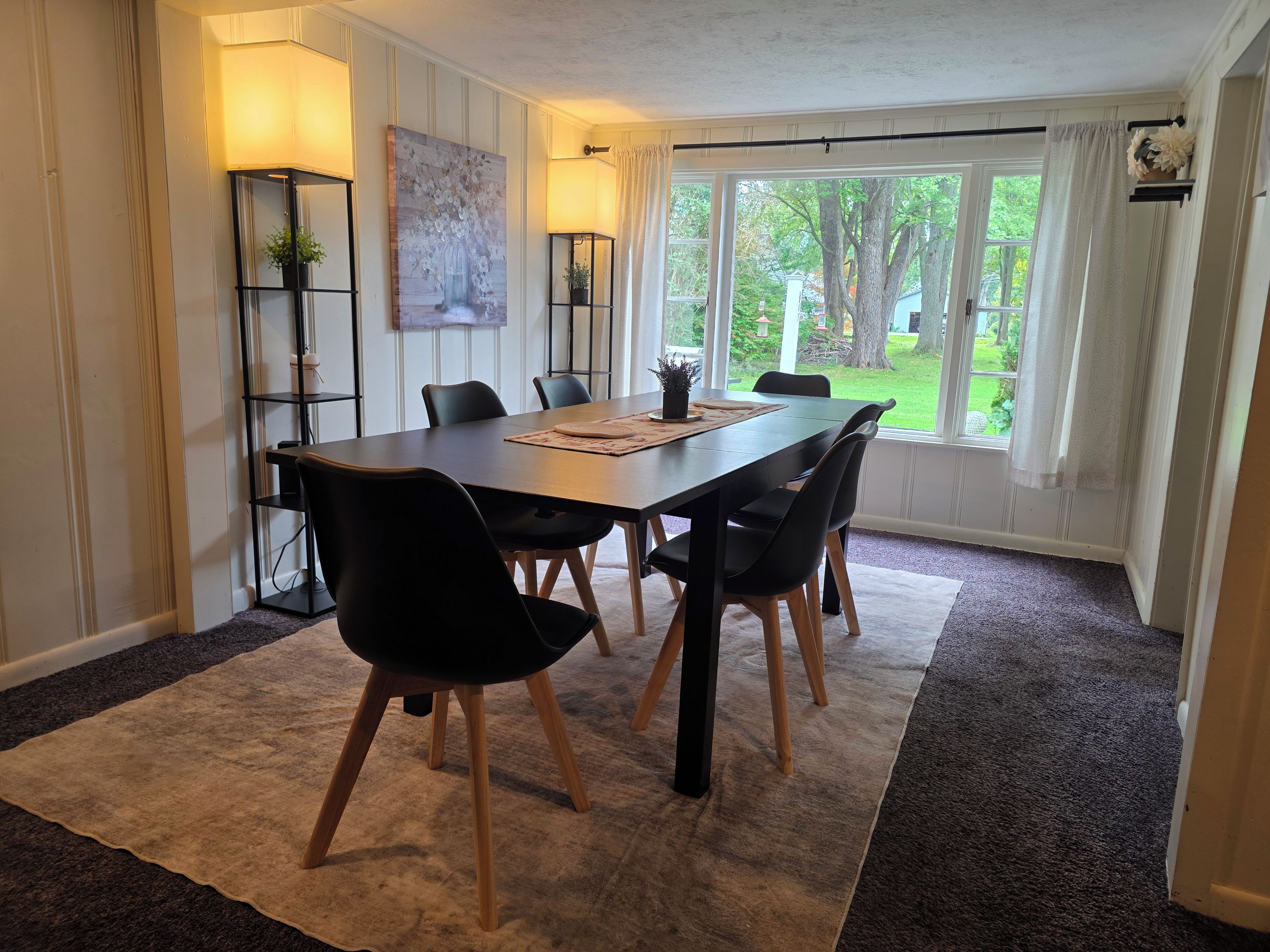 Un comedor con mesa, sillas y vistas al exterior.