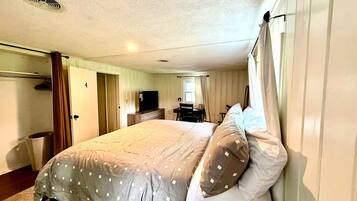 A bedroom with a large bed, a television, a desk, and a chair.