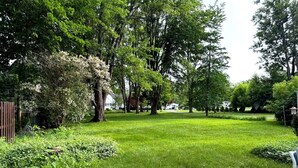 A well-maintained backyard with a wooden deck, lush green lawn, and mature trees.
