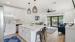 A modern kitchen with white cabinets, a large island, pendant lights, and a ceiling fan. - Seagrove Crush- Renovated- Steps to Private Beach! (Santa Rosa Beach)