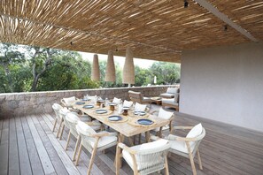 A wooden deck with a table set for dining, surrounded by wicker chairs, under a bamboo canopy. - Contemporary sea-view villa with large infinity pool and walking distance to the beach (Zonza)