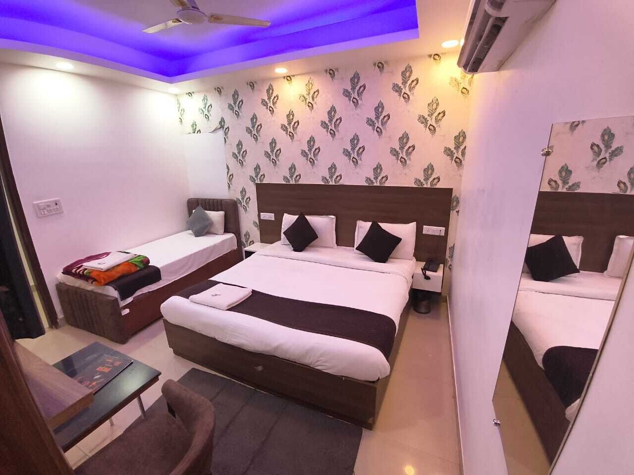 Quarto de hotel com uma cama grande, uma cama menor, uma escrivaninha e uma cadeira.