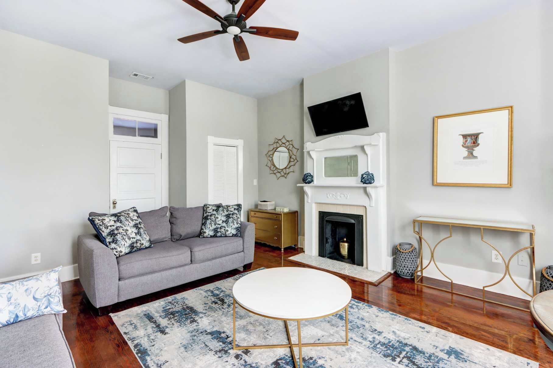 A living room with a gray sofa, a round white coffee table, a fireplace, and a television mounted on the wall.