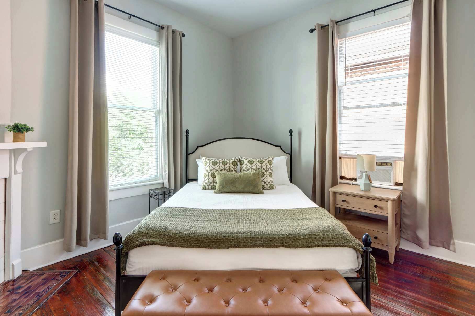 Une chambre à coucher avec un lit, une table de chevet, une lampe et des rideaux.