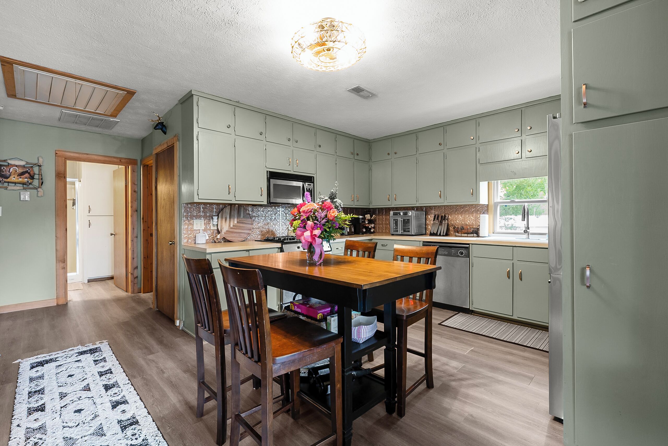 A kitchen with wooden cabinets, a dining table with chairs, a microwave, and a refrigerator.