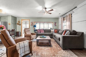A spacious living room with a sectional sofa, a coffee table, and a dining area with a table and chairs.
