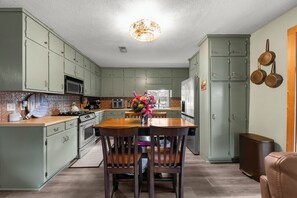 A kitchen with green cabinets, a wooden dining table, and chairs.