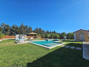 A backyard with a swimming pool, a small shed, and a patio area with chairs and umbrellas. - Villa Nectaris-bizerte (Menzel Jemil)