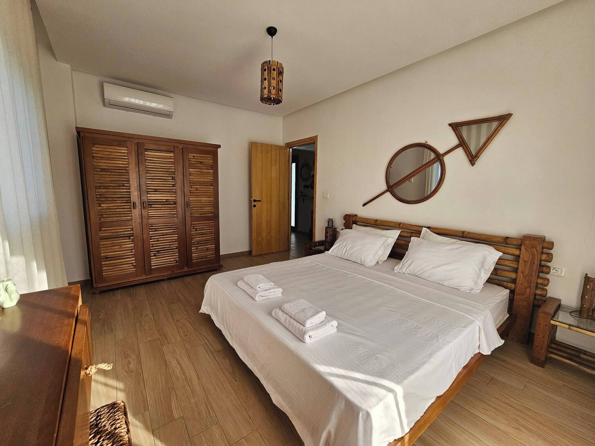 Une chambre à coucher avec un lit en bois, une armoire et un miroir au mur.