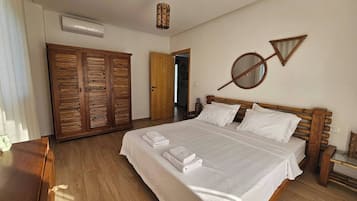 Une chambre à coucher avec un lit en bois, une armoire et un miroir au mur.