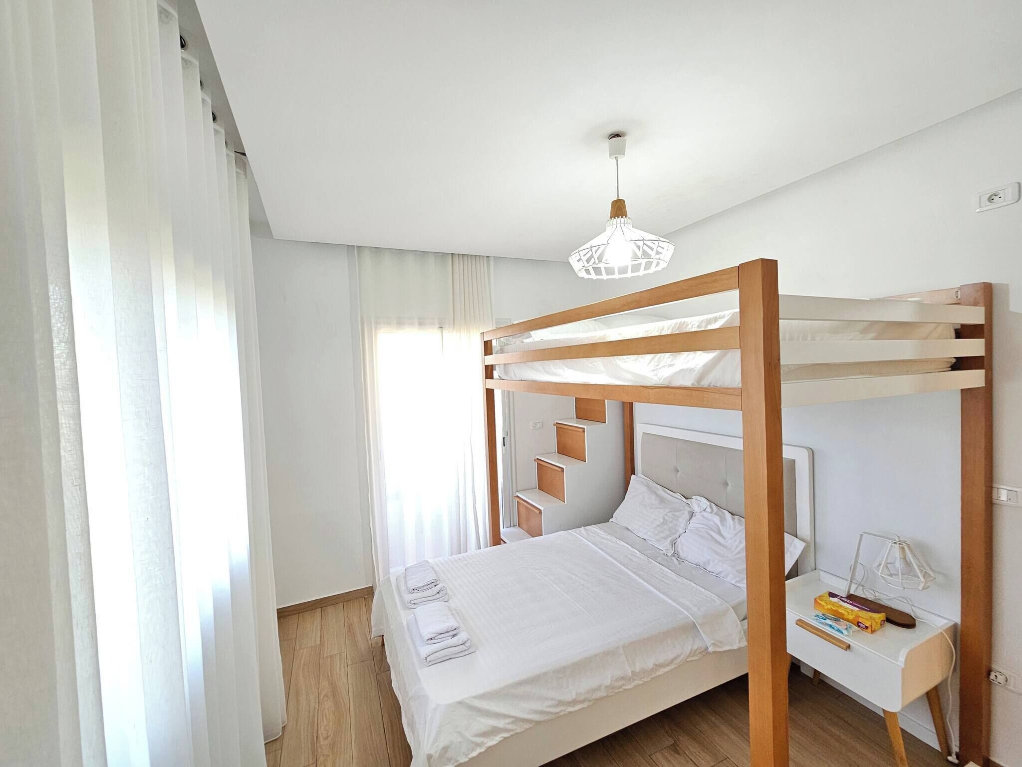A bunk bed room with a desk and a hanging light fixture.
