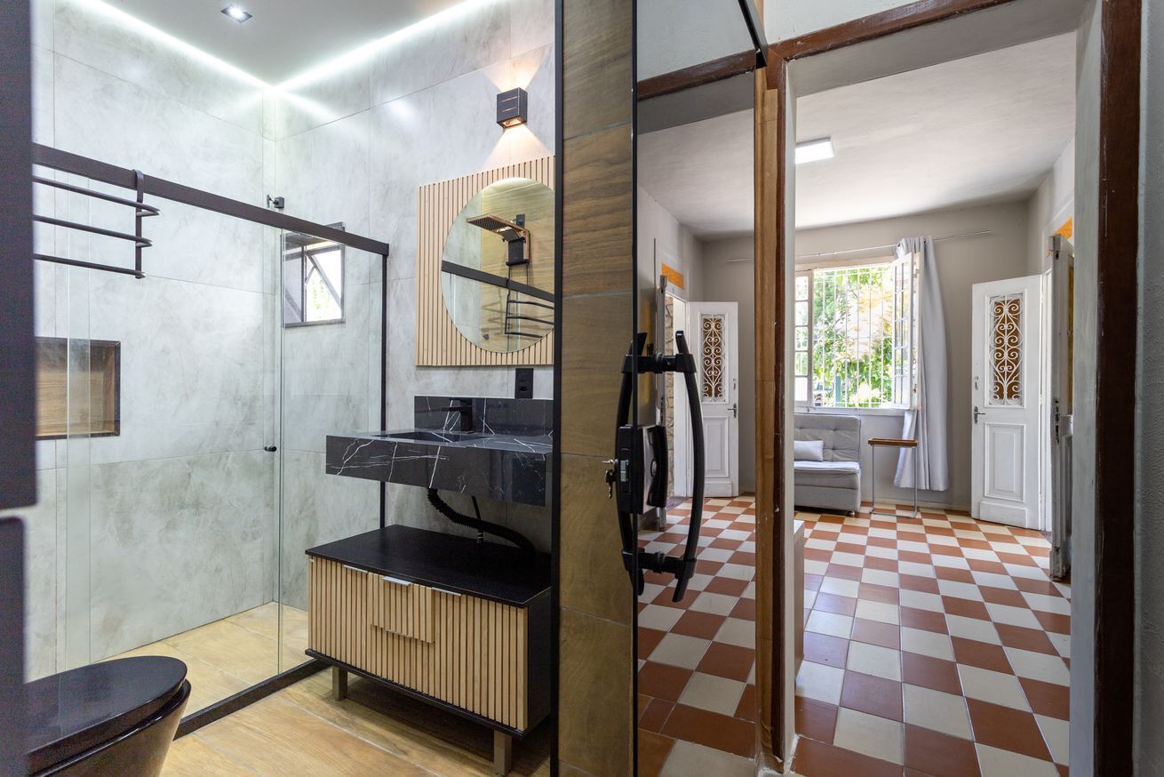 Ein modernes Badezimmer mit einer Duschkabine aus Glas, einem Holzbadezimmer-Möbel und einem großen Spiegel.
