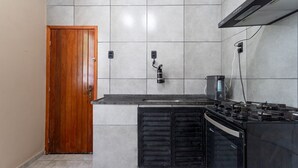A kitchen with a wooden door, tiled backsplash, a stove, and a coffee maker. - Casa p 8 Pessoas c Varanda a 400m Museu Imperial (Petrópolis)
